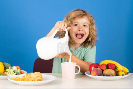 Téléchargez les photos : Enfant excité avec du lait laitier. Un enfant en bonne santé verse le lait de la cruche - en image libre de droit