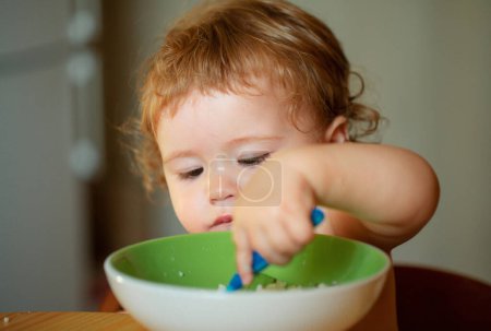 Photo for Family, food, child, eating and parenthood concept. Happy baby eating himself with a spoon - Royalty Free Image