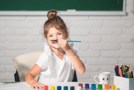 Foto de Child girl drawing with coloring pens paintind. Portrait of adorable little girl smiling happily while enjoying art and craft lesson in school. Kids creative education concept. - Imagen libre de derechos