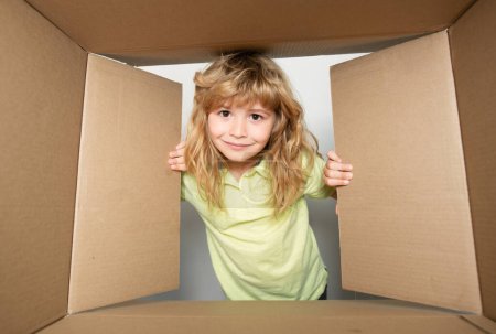 Photo for Kid open paper cardboard box. Cheerful cute child opening a present. Cardboard boxes, parcels. Delivery service concept - Royalty Free Image