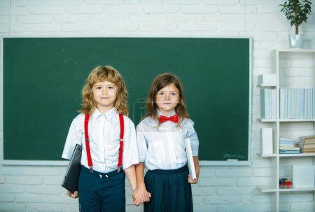 Photo for School friends. Two school kids, girl and boy holding hands going at school class in first class - Royalty Free Image