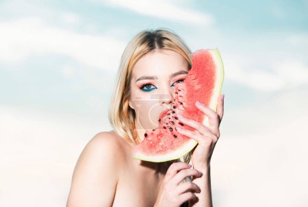 Photo for Portrait of a beautiful young blonde woman with blue eyes eating watermelon. Sexy blond woman with summer fashion make-up lick watermelon. Beauty face - Royalty Free Image