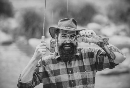 Téléchargez les photos : Loisirs de pêche et week-end d'été. Homme barbu drôle pêcheur avec canne à pêche et filet. poisson oeil amusant - en image libre de droit