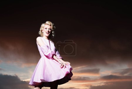Frau im Monroe-Kleid am dramatischen Himmel. Attraktive Frau in modischem Outfit draußen. Outdoor-Mode Foto von jungen schönen Dame genießen Frühling