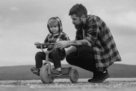 Photo for Father and son learning to ride a bicycle. Little boy learn to ride a bike with his daddy. Dad teaching child boy to ride bicycle - Royalty Free Image