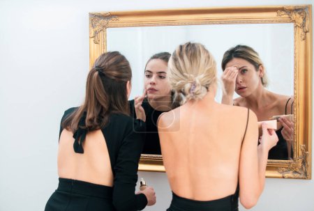 Photo for Gorgeous young woman face portrait. Women girlfriends applying make-up preparing for party, looking in mirror - Royalty Free Image