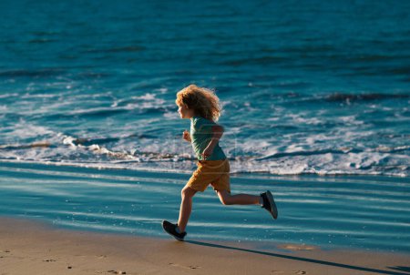 Photo for Child running through water close to shore along the sea beach. A boy runs along the sea coast. Rest of children on summer vacation. Outdoor sports and fitness for children - Royalty Free Image