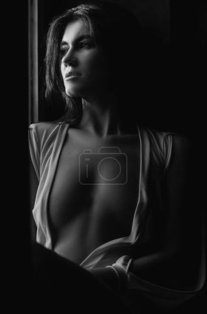 Photo for Sensual girl. Portrait of elegant woman with light on a black background. Beautiful female face in the darkness - Royalty Free Image
