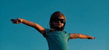 Téléchargez les photos : Enfants avec lunettes de pilote et casque jouant avec un avion en bois vintage à l'extérieur. Portrait d'enfants contre le ciel d'été. Concept de voyage et liberté - en image libre de droit