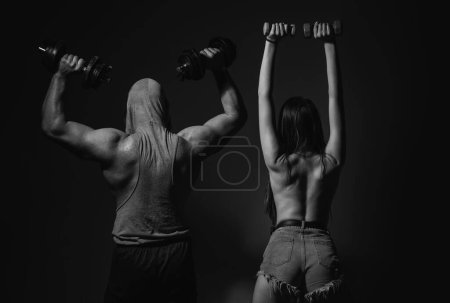 Photo for Couple of fit bodybuilders, muscular man and beautiful sexy girl with dumbbells. Sport couple. Muscular man with naked body, fitness woman with dumbbells on a dark background, back - Royalty Free Image