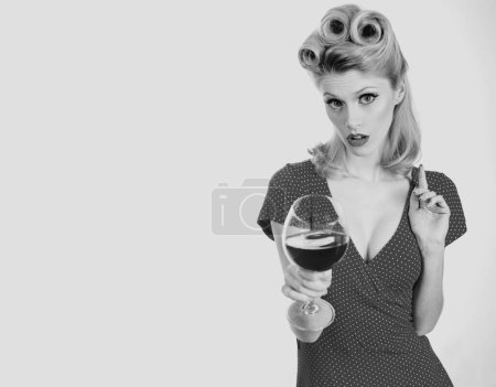 Téléchargez les photos : Woman with glass of red wine. Beautiful woman drinking red wine, isolated on white. Retro girl with stylish makeup and retro hairstyle in white dress tasting red wine - en image libre de droit