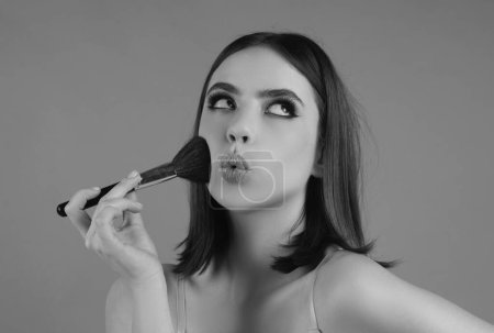 Téléchargez les photos : Portrait of a funny beautiful young girl with makeup blusher brush, bright make-up - en image libre de droit