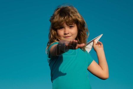 Photo for Young boy with paper plane against blue sky. Kid playing with paper airplane on sunny day - Royalty Free Image