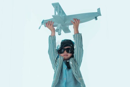 Photo for Kid with pilot goggles and helmet dreaming and plays with a toy plane in the park. Dreams of travel. Development, growth, dreams and plans. Imagination and dream concept - Royalty Free Image
