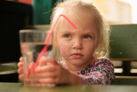 Téléchargez les photos : L'enfant boit de l'eau. drôle bébé fille boire à partir de verre - en image libre de droit