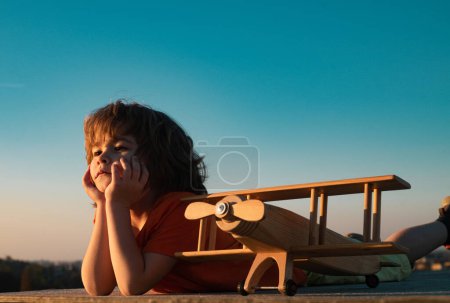 Photo for Little boy 7 year old with wooden plane, boy wants to become pilot and astronaut. Happy child play with toy airplane. Kids pilot dreams of flying - Royalty Free Image