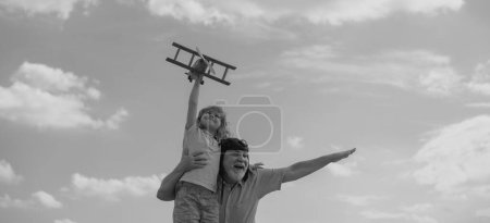 Téléchargez les photos : Grandfather and grandson with toy plane over blue sky and clouds background. Two men generation grandfather and grandson playing outdoors - en image libre de droit