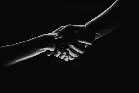 Handshake hand, arm on salvation. Close up help hand. Two hands, helping arm of a friend, teamwork. Rescue, helping gesture or hands, agreement. Black background