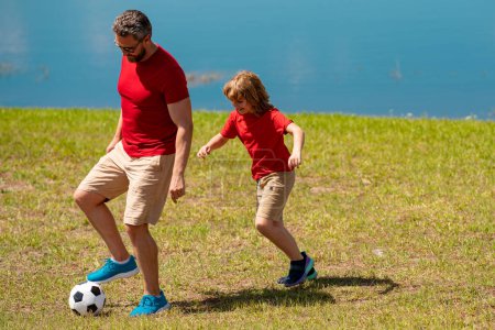 Photo for Father and son playing soccer football together. Father and son hours practicing passing kicking soccer ball. Dad and son playing soccer together on green meadow. Father and son on soccer pitch - Royalty Free Image