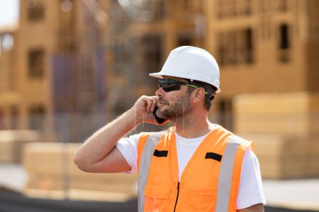 Photo for Worker using phone, builder taking on phone a break from work. Architect with mobile phone. Worker man on the building construction. Construction site worker in helmet work outdoors - Royalty Free Image