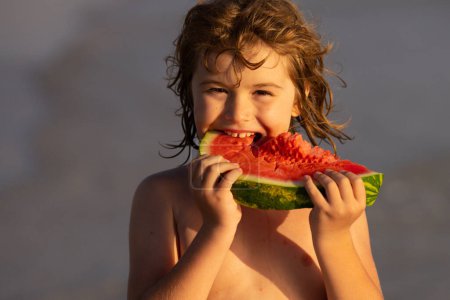 Photo for Vacation and traveling with kids. Summer watermelon fruit for children. Child play by the sea and eat watermelon. Little boy biting watermelon on beach. Kid is picking watermelon outdoor - Royalty Free Image