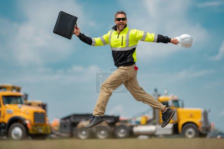 Photo for Construction man excited jump with helmet. Builder in helmet outdoor portrait. Worker in hardhat. Construction engineer worker in builder uniform on construction. Excited foreman jump - Royalty Free Image