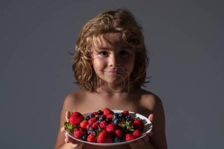 Téléchargez les photos : Une nourriture saine. Funny kid tenir assiette de mélange de fruits d'été. Fruits de fraise bio sains, saison estivale - en image libre de droit