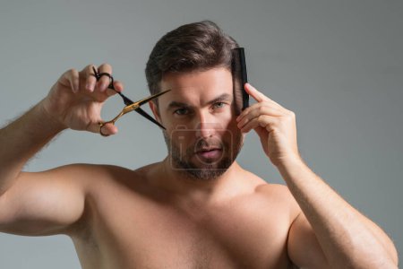 Téléchargez les photos : Un homme caucasien essayant de se faire couper les cheveux avec des ciseaux. Une coupe masculine. Ciseaux de coiffeur, salon de coiffure. Ciseaux de coiffeur. Concept de coupe de cheveux. Hommes coiffure et coupe de cheveux - en image libre de droit