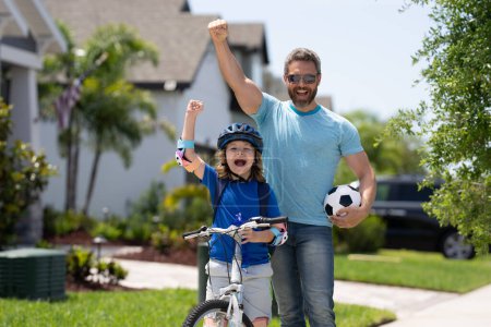 Photo for Happy family. Father and son riding bike in park. Sporty family. Excited father and son with winning gesture. Father teaching son riding bike. Fatherhood. Support parent. Fathers day. Child care - Royalty Free Image