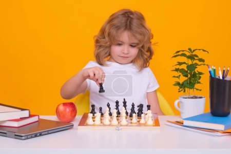 Téléchargez les photos : Enfant avec échecs sur fond de studio isolé jaune. L'enfant pense au jeu d'échecs. Étudiant intelligent, intelligent et intelligent. Jeux pour le concept intelligence cérébrale - en image libre de droit