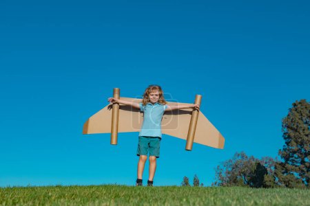 Photo for Child boy playing with cardboard toy airplane wings craft in sky with copy space for text. Creative with family and dreaming of flying concept - Royalty Free Image