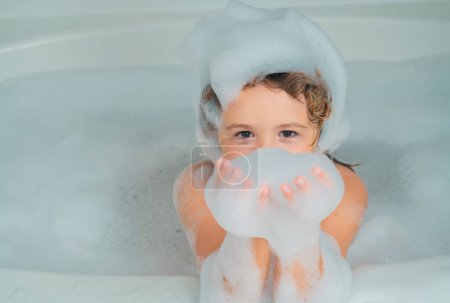 Foto de Divertido niño jugando con espuma en el baño - Imagen libre de derechos