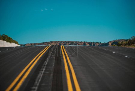 Carretera de asfalto vacía y cielo azul. Panorama del camino en el soleado día de verano