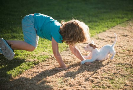 Téléchargez les photos : Enfant mignon profiter avec son meilleur chien ami. Jeu de chien drôle. Enfants jouant avec son chien de compagnie - en image libre de droit