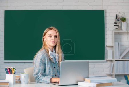 Photo for Young teacher. Portrait of young female college student studying in classroom on class with blackboard background - Royalty Free Image