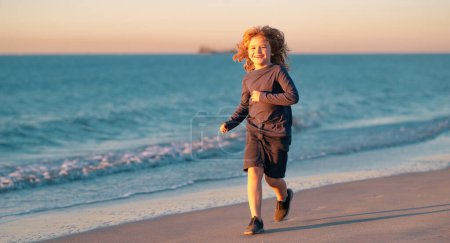 Téléchargez les photos : Un enfant court au bord de la mer. Des enfants qui courent sur la plage. Vacances d'été. Joyeux gamin jouant sur la plage. Bonne enfance. Vacances d'été avec enfant - en image libre de droit