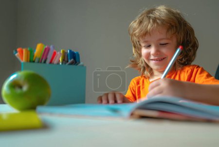 Téléchargez les photos : Le petit garçon fait ses devoirs pour l'école primaire. - en image libre de droit