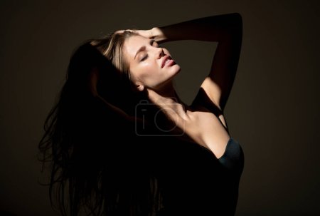 Foto de Retrato de mujer elegante con luz sobre fondo negro. Chica sensual con luz de sombra de arte. Hermoso rostro femenino en la oscuridad - Imagen libre de derechos