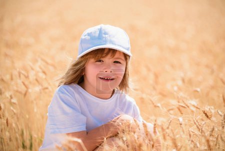 Foto de Niño en el campo de trigo. Niño señalando espiga de trigo en el día de verano en la granja - Imagen libre de derechos