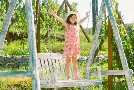Photo for Little child girl is swinging on a swing in summer park. Sunny joyful summer day. Child swinging on playground on sunny summer day in a park. Summer outdoor activity. Kid playing - Royalty Free Image