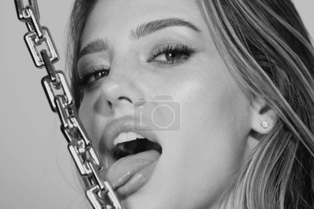Foto de Sensual mujer de cerca retrato con cadena dorada en la boca. Modelo femenino lamer cadena dorada, cara sexy - Imagen libre de derechos