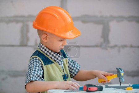 Photo for Child in helmet is construction worker. Foreman kid work in the hard hat making repairs. Childhood development. Little builder engineer. Improve your childhood - Royalty Free Image