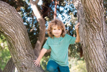 Foto de Niño tratando de trepar a un árbol. Niños trepando un árbol. Niño jugando y trepando a un árbol y colgando rama. Niño feliz disfrutando del día de verano en un jardín - Imagen libre de derechos