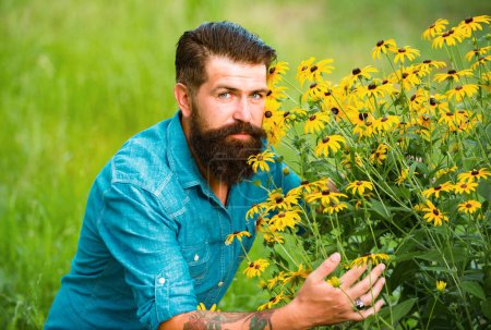 Foto de Hombre barbudo despreocupado al aire libre. Flores de primavera. Unidad con la naturaleza. Campo y prado - Imagen libre de derechos