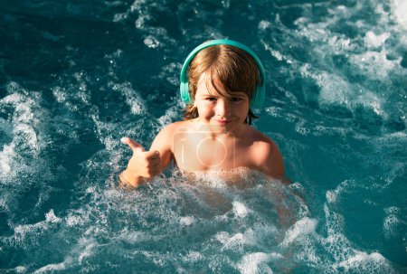 Téléchargez les photos : Enfant heureux jouant dans la piscine extérieure pendant la chaude journée d'été. Les enfants apprennent à nager. Enfant dans l'eau. Les enfants jouent dans une station tropicale. Vacances familiales à la plage - en image libre de droit