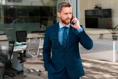 Photo for Businessman talking on phone. Businessman in front office. Handsome business man. Business portrait of serious business man outdoor. Middle aged hispanic business man with phone on office building - Royalty Free Image