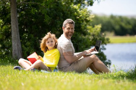 Photo for Father and son reading book in park, man encourages boy to knowledge, family education. Father and child read book together outdoor. Happy parent reading with child book on summer nature in park - Royalty Free Image