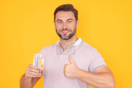 Téléchargez les photos : L'homme boit de l'eau. Portrait d'homme souriant heureux avec un verre d'eau douce. Un type soif. Rafraîchissant. Bilan hydrique. Portrait de l'homme buvant de l'eau pure tranquille - en image libre de droit