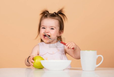 Photo for Baby child eating food. Happy smiling baby girl with spoon eats itself - Royalty Free Image