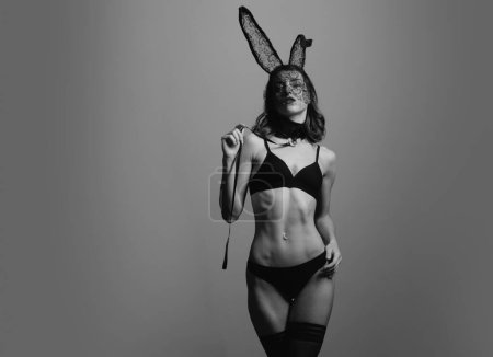 Téléchargez les photos : Belle jeune femme sexy portant un masque noir lapin de Pâques et semble très sensuelle. Pâques de lapin. Fille nue avec un corps parfait se préparent pour les vacances. Modèle de bikini - en image libre de droit